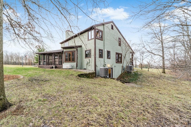 rear view of house with a lawn, central AC, and a sunroom