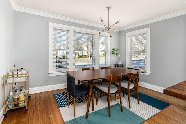 dining space with hardwood / wood-style flooring, ornamental molding, and a notable chandelier