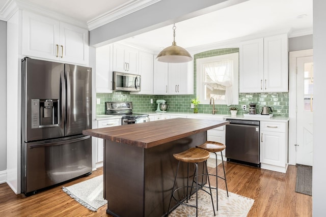 kitchen with wood counters, white cabinetry, pendant lighting, and appliances with stainless steel finishes