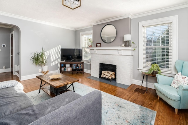 living room with ornamental molding, wood-type flooring, and a fireplace