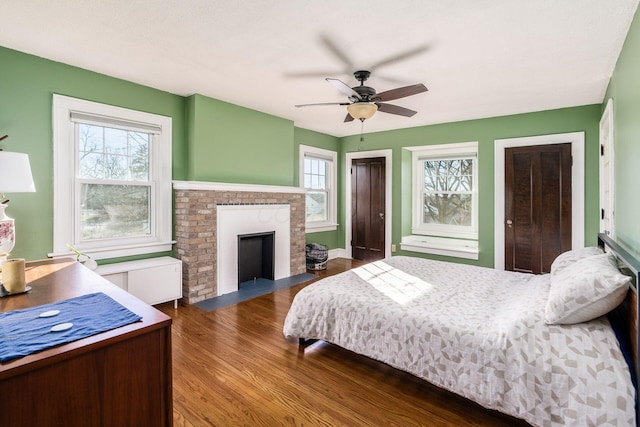 bedroom featuring multiple closets, a fireplace, dark hardwood / wood-style flooring, and multiple windows