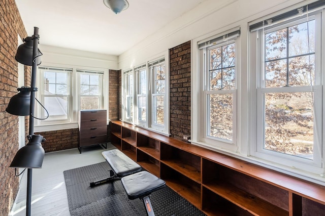 workout room with brick wall and light wood-type flooring