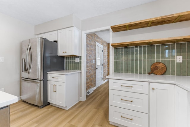 kitchen featuring tasteful backsplash, white cabinets, stainless steel refrigerator with ice dispenser, and light wood-type flooring