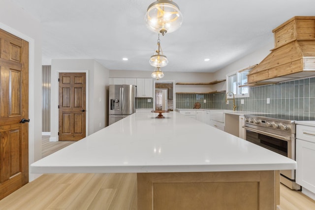 kitchen with appliances with stainless steel finishes, premium range hood, white cabinets, hanging light fixtures, and a large island