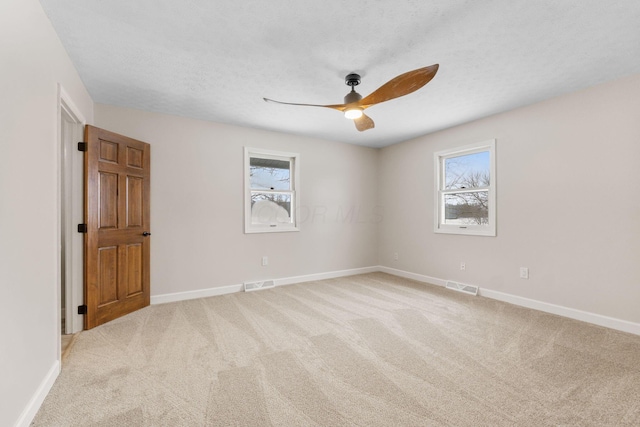 carpeted spare room with a textured ceiling and ceiling fan