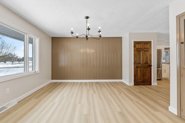 unfurnished room featuring light hardwood / wood-style floors and an inviting chandelier