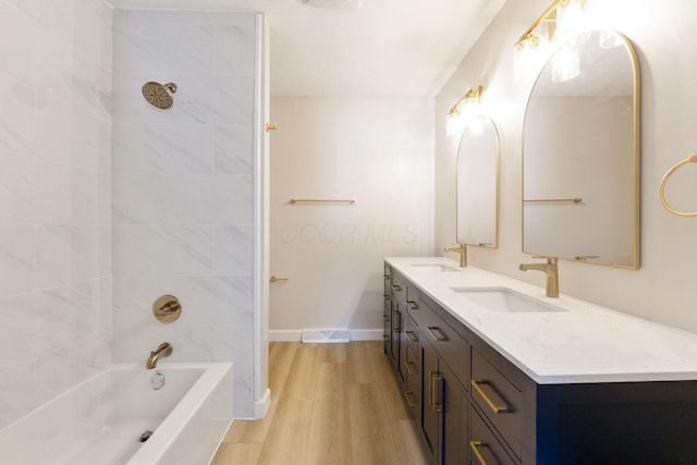 bathroom with hardwood / wood-style flooring, tiled shower / bath combo, and vanity