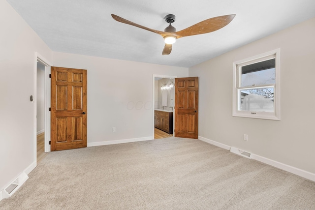 unfurnished bedroom featuring light carpet, ensuite bathroom, and ceiling fan