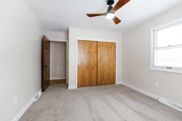 unfurnished bedroom featuring ceiling fan, light carpet, and a closet