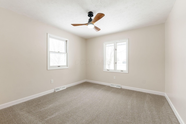 empty room with carpet flooring, ceiling fan, and a healthy amount of sunlight