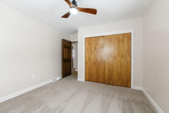 unfurnished bedroom featuring ceiling fan, light colored carpet, and a closet