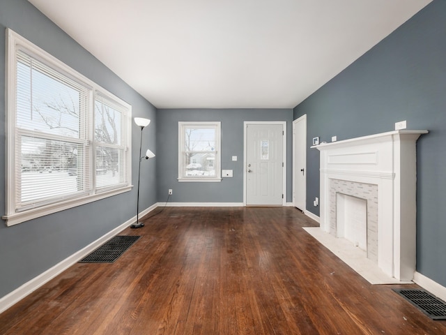 unfurnished living room with a tile fireplace, dark hardwood / wood-style flooring, and a healthy amount of sunlight