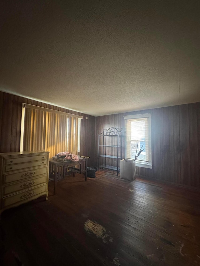 interior space with a textured ceiling, wood walls, and dark hardwood / wood-style floors