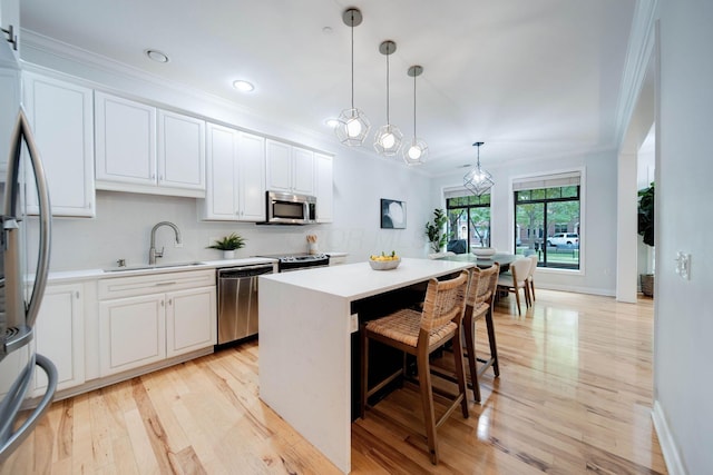 kitchen featuring sink, white cabinetry, hanging light fixtures, and appliances with stainless steel finishes