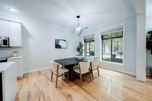 dining space with light hardwood / wood-style floors, crown molding, and a chandelier