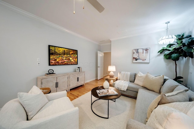 living room with light wood-type flooring, a notable chandelier, and ornamental molding