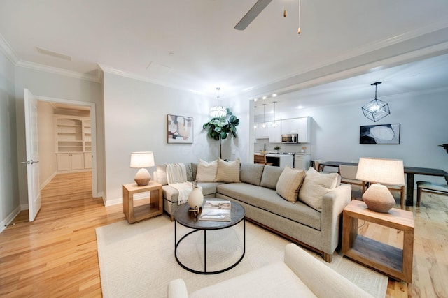 living room featuring light wood-type flooring, built in features, ceiling fan, and ornamental molding