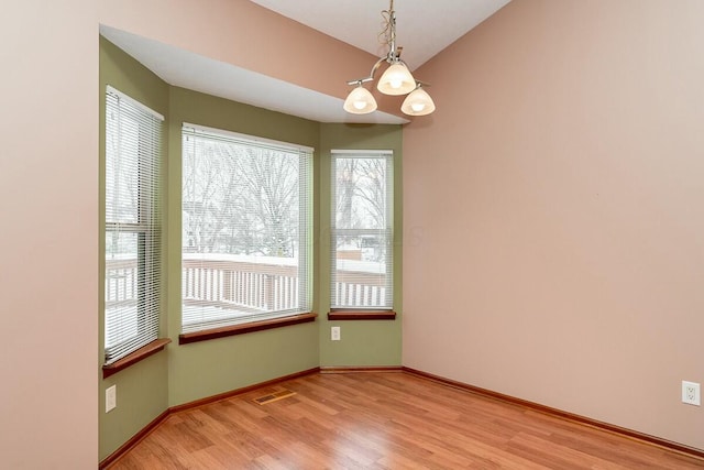 empty room with a chandelier and wood-type flooring