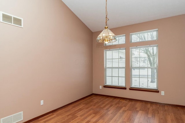 unfurnished room featuring wood-type flooring and an inviting chandelier