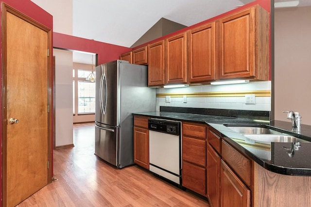 kitchen featuring decorative backsplash, stainless steel fridge, white dishwasher, vaulted ceiling, and sink