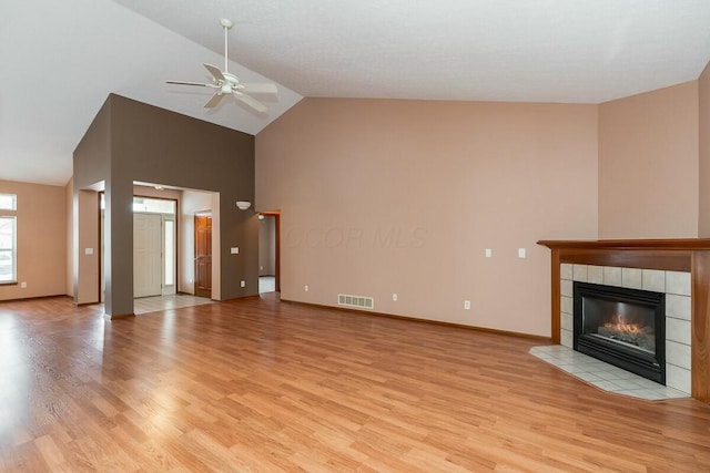 unfurnished living room featuring a tile fireplace, light hardwood / wood-style floors, vaulted ceiling, and ceiling fan