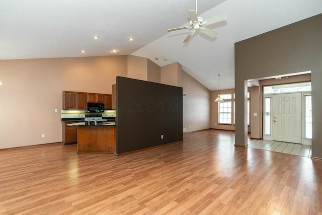 kitchen featuring ceiling fan, light wood-type flooring, hanging light fixtures, and high vaulted ceiling