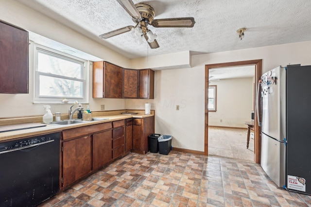 kitchen with a textured ceiling, dark brown cabinetry, sink, dishwasher, and stainless steel refrigerator