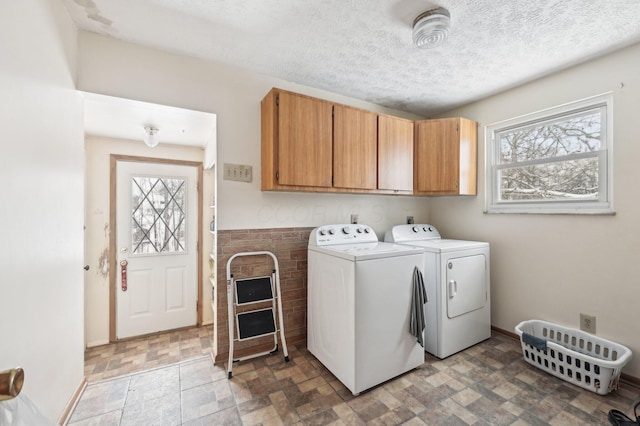 washroom featuring cabinets, a textured ceiling, and washer and clothes dryer