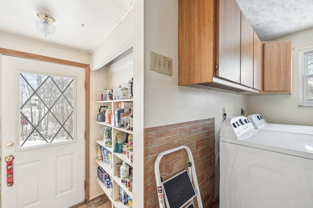 clothes washing area with washer and clothes dryer, cabinets, and a textured ceiling