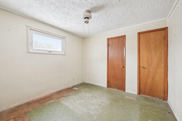 unfurnished bedroom with ceiling fan, crown molding, a textured ceiling, and two closets