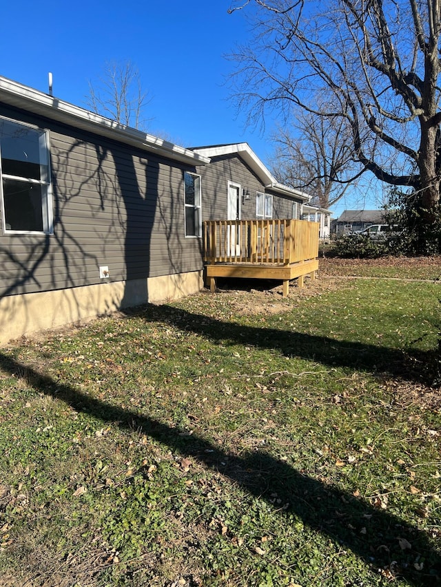 back of house featuring a lawn and a wooden deck