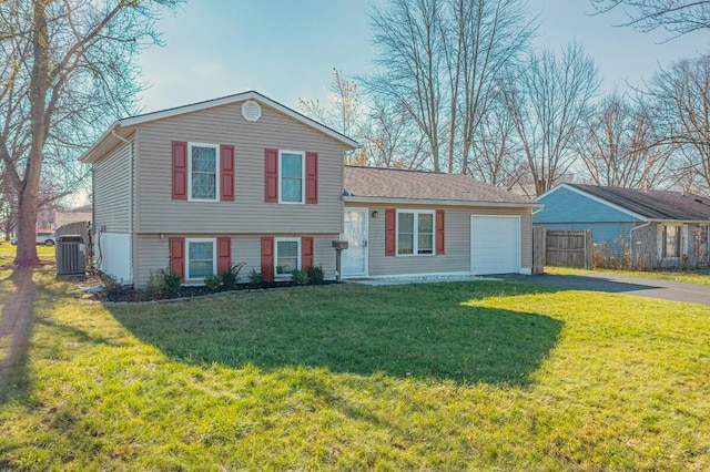 tri-level home featuring cooling unit, a front yard, and a garage