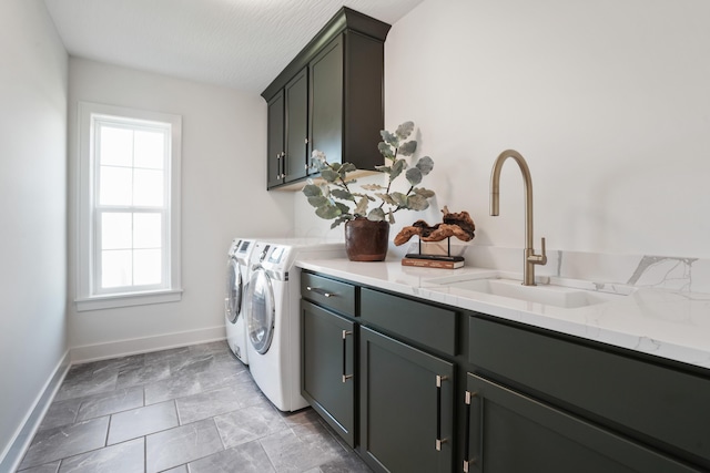 laundry room featuring washing machine and clothes dryer, sink, and cabinets