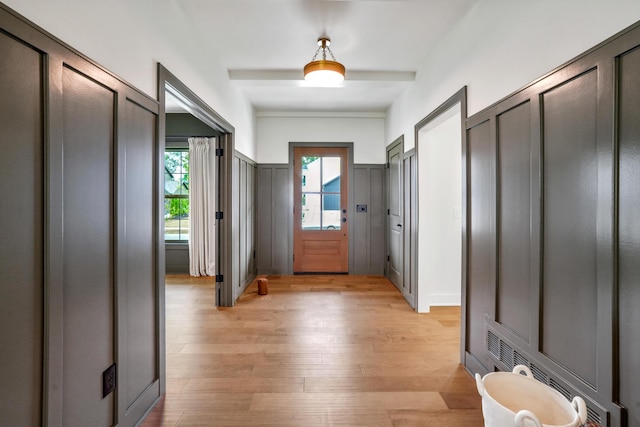 doorway with beamed ceiling and light hardwood / wood-style floors