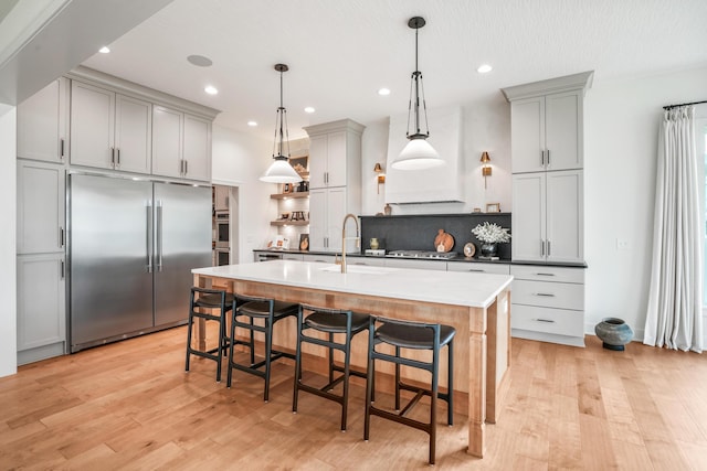 kitchen with tasteful backsplash, stainless steel built in refrigerator, sink, pendant lighting, and gray cabinets