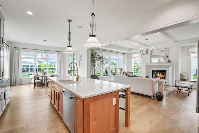 kitchen with a kitchen breakfast bar, a kitchen island with sink, sink, pendant lighting, and beam ceiling