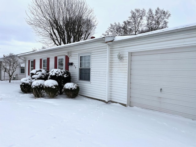 view of snow covered exterior with a garage