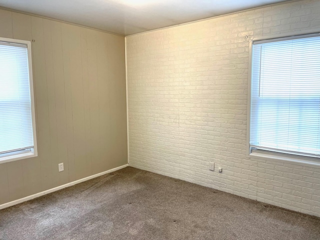 empty room with carpet floors and brick wall