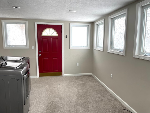 carpeted entrance foyer with washer and clothes dryer and a textured ceiling