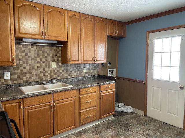 kitchen featuring a textured ceiling, tasteful backsplash, crown molding, and sink