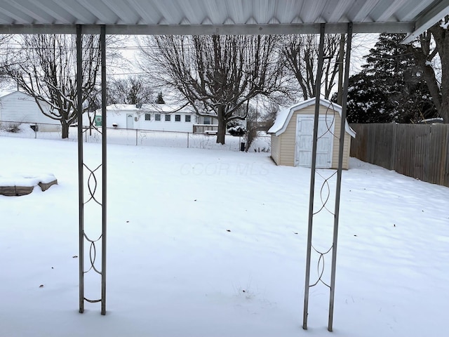 yard layered in snow featuring a storage shed