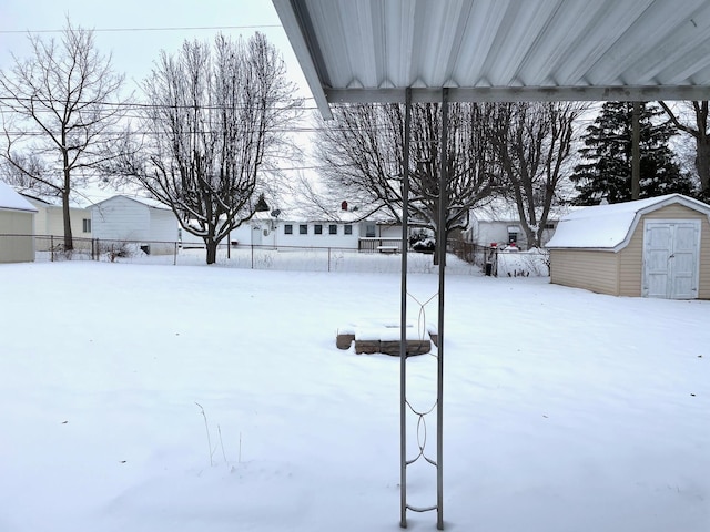 yard covered in snow with a storage unit