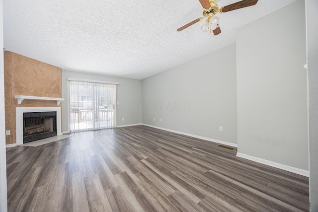 unfurnished living room featuring a fireplace, a textured ceiling, dark hardwood / wood-style floors, and ceiling fan