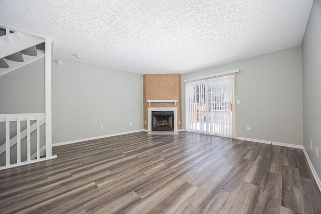 unfurnished living room with dark hardwood / wood-style flooring, a textured ceiling, and a large fireplace