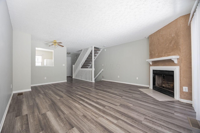 unfurnished living room featuring ceiling fan, hardwood / wood-style floors, and a textured ceiling