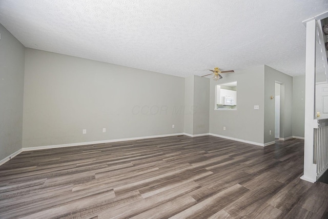 unfurnished living room featuring ceiling fan, dark wood-type flooring, and a textured ceiling