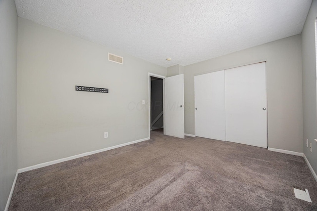 unfurnished bedroom featuring carpet flooring, a closet, and a textured ceiling