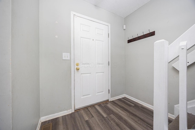 doorway to outside featuring a textured ceiling and dark hardwood / wood-style floors