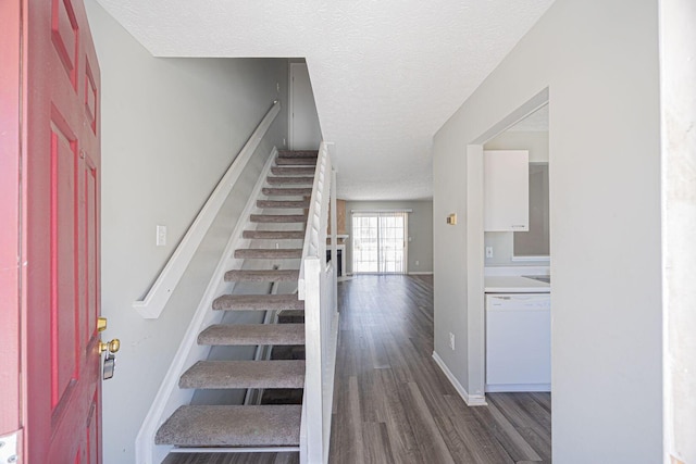 stairway with wood-type flooring and a textured ceiling