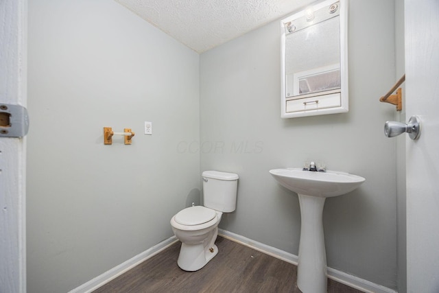 bathroom featuring hardwood / wood-style flooring, sink, a textured ceiling, and toilet